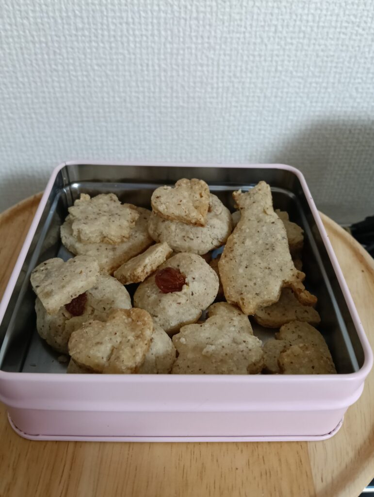 ハート、さくら、猫などの型に抜かれたアレルゲンフリーのクッキーがピンクの缶に詰められている。